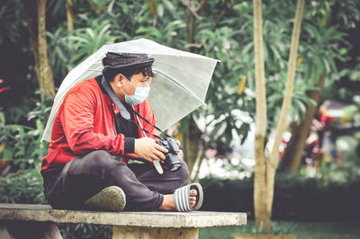 Man wearing hat sitting against plants