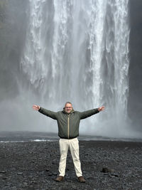 Rear view of woman standing against waterfall