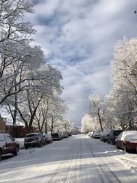 Cars on road by snow covered city against sky