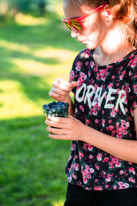 Midsection of woman holding ice cream standing on field