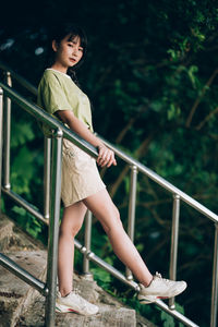 Portrait of young woman standing by railing