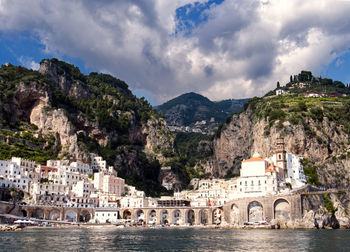 Buildings by river against mountain