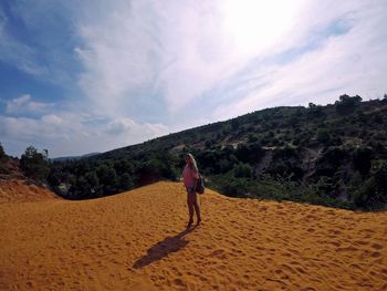 Woman with arms raised on mountain against sky