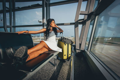 Woman with luggage sitting at airport departure area