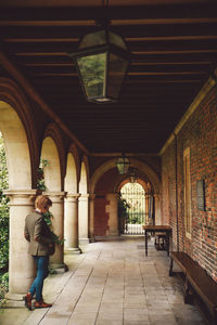 Full length of woman standing by architectural columns in corridor