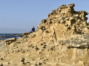 Rock formations on beach against clear sky