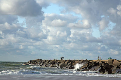 Rocks by sea against cloudy sky