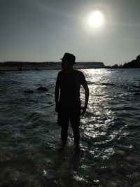 Silhouette man standing on sea against sky