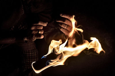 Close-up of hand holding fire against black background