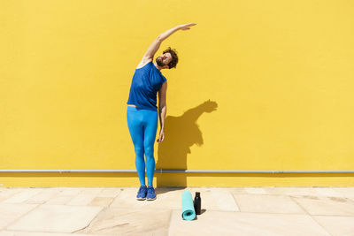 Full length of woman standing against yellow wall