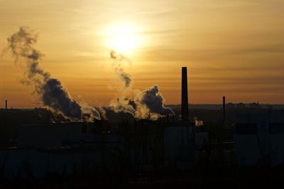 Smoke emitting from factory against sky during sunset