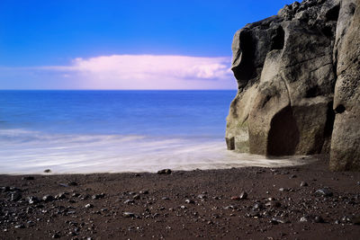 Rock formation on beach against sky