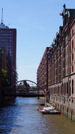 Boats in river by buildings in city against sky