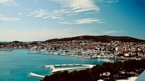 Aerial view of city by sea against sky