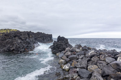 Rocks on sea shore against sky