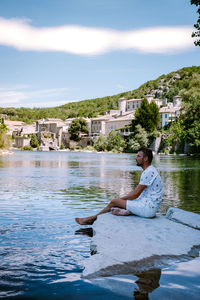 Man sitting by swimming pool in lake against sky