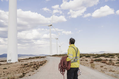 Engineer with rope looking at wind turbines at wind farm