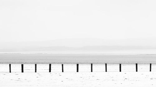 Wooden posts on beach against clear sky