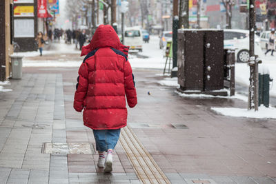 Rear view of woman walking on footpath in winter