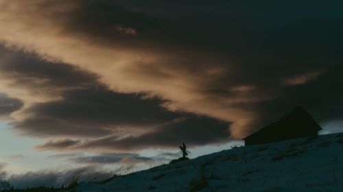 Silhouette of person standing by mountain against sky