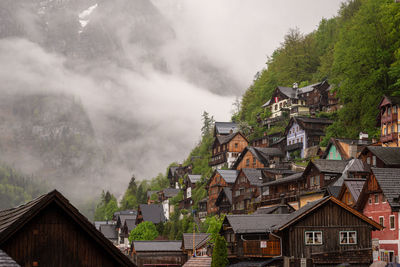 Houses by trees and buildings against sky