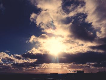 Low angle view of sunlight streaming through clouds