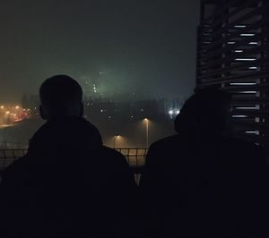 Low section of silhouette men against illuminated lights