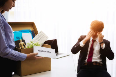 Woman giving resignation to businessman at desk in office