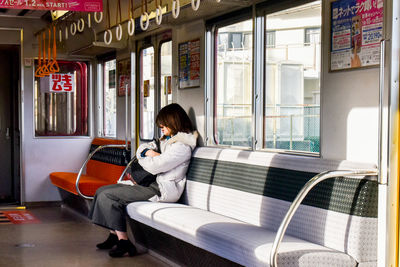 Full length of woman sitting on seat in bedroom