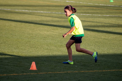 Side view of girl playing on soccer field