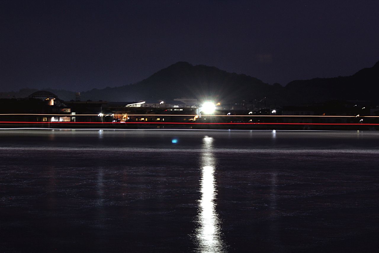 mountain, illuminated, sky, night, water, no people, nature, light trail, scenics - nature, beauty in nature, waterfront, motion, long exposure, speed, transportation, reflection, lake, architecture, tranquil scene, outdoors