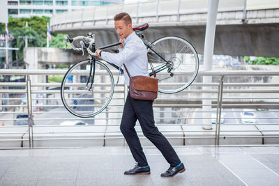 Full length of man holding bicycle in city