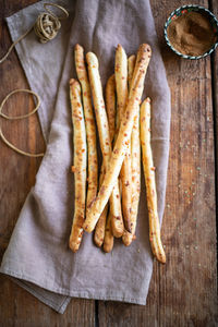 Grissini - italian bread sticks with dried herbs on a wooden background.