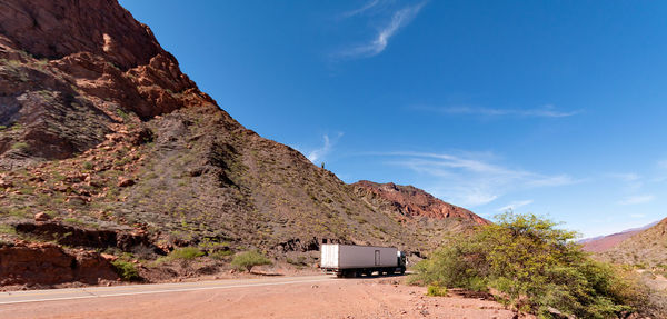 Road by mountain against blue sky