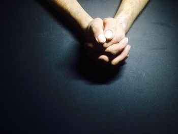 Cropped image of man with hands clasped on black table