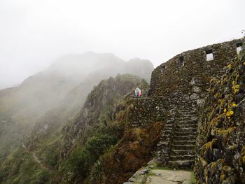 Low angle view of young man on cliff against sky