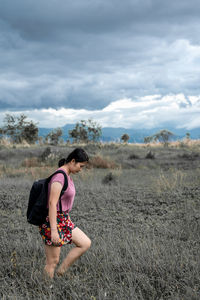 Side view of woman standing on field against sky