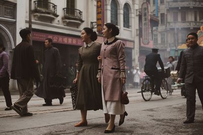 Rear view of people walking on street in city