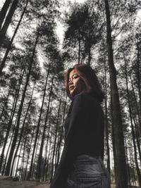 Side view of young woman standing in forest