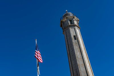 Low angle view of flags against clear blue sky