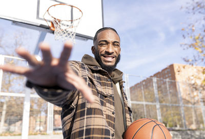 Portrait of smiling man standing against basketball hoop