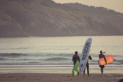 Rear view of people at beach against sky