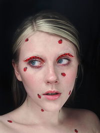 Close-up portrait of a young woman with ladybugs