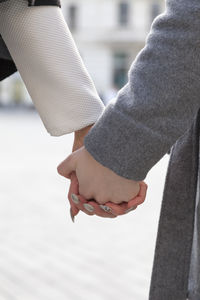 Cropped hands of couple holding hands on street