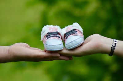 Cropped hands of couple holding baby shoes