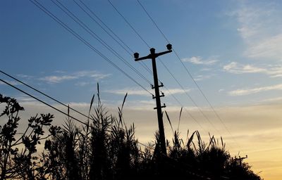 Low angle view of silhouette electricity pylon against sky during sunset