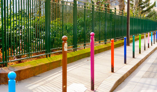 Colorful bollards on footpath along fence