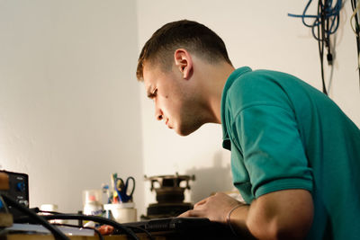 Repairman working meticulously on a laptop, using a soldering tool to fix electronic components. 