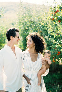 Cheerful parents with baby at farm