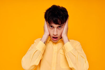 Portrait of young woman standing against yellow background